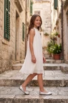 Robe Rozalia blanche plissée en extérieur, sur des escaliers – vue de côté