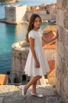 Robe Rumi blanche à manches tulipe en extérieur, près d'un mur de pierre